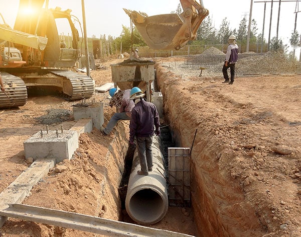Two Workers Are Installing Concrete Drains On The Side Of
